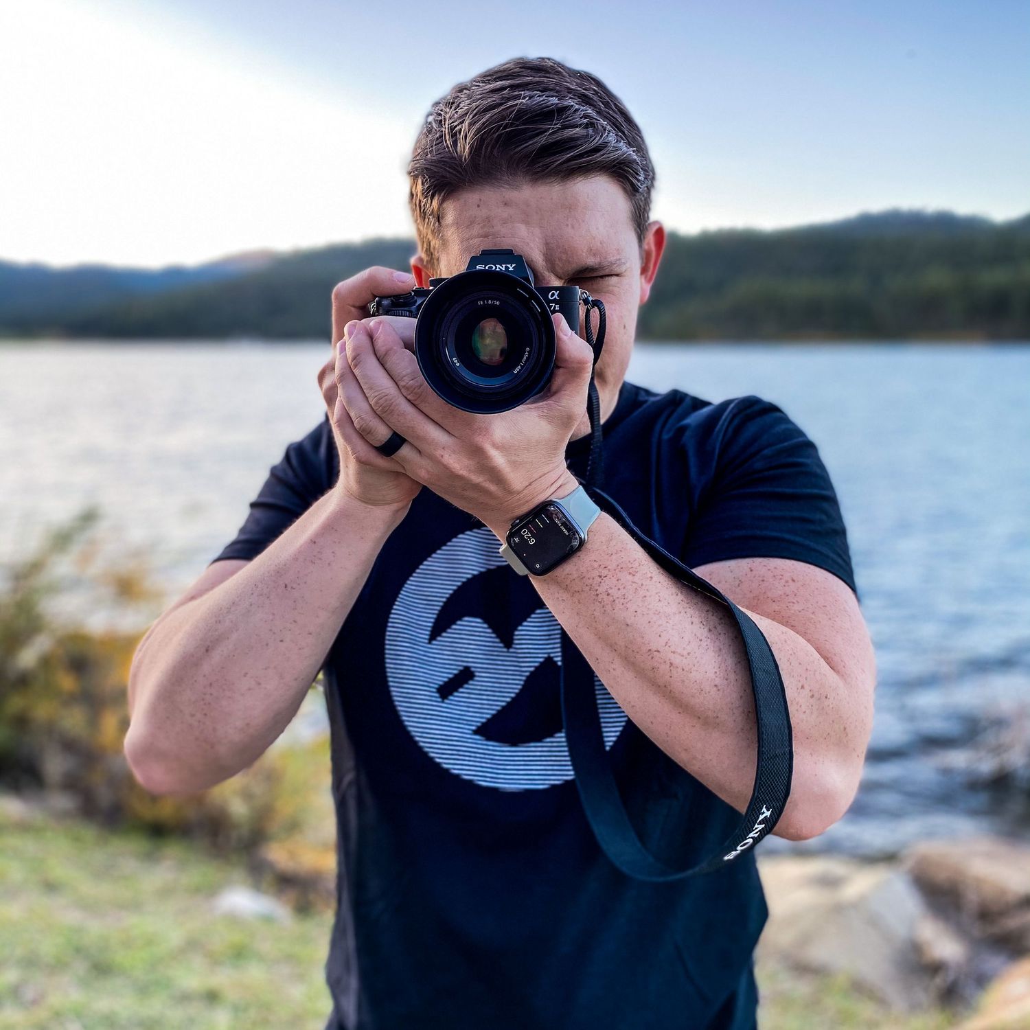 Photographer in navy t-shirt shooting with professional camera by a lake. alt="Professional  photography in Lubbock TX by H & Co. Creative