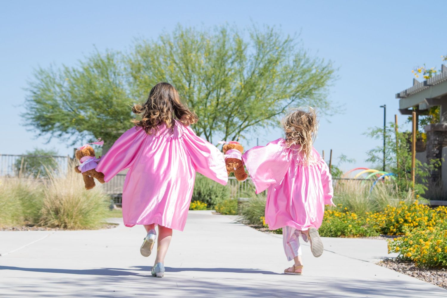 two girls run in their pink graduation robes in rural Marana, Arizona