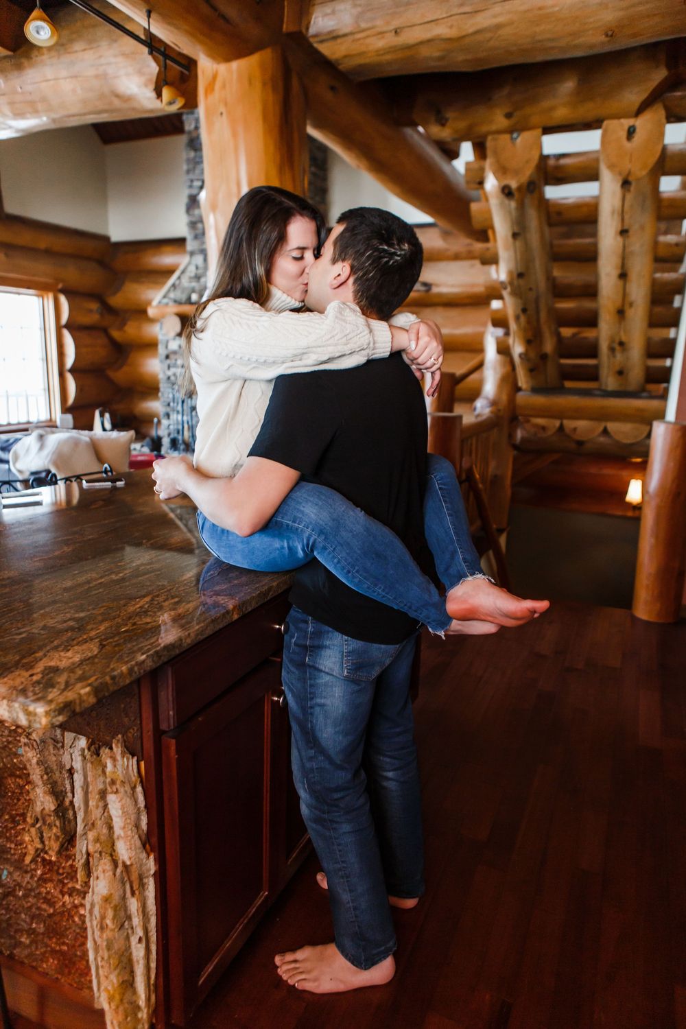 Romantic couple shares intimate moments in a rustic log cabin with exposed wooden beams and natural lighting.