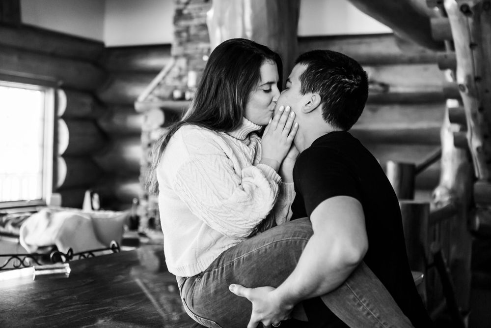 A romantic black and white photo of a couple sharing an intimate moment at a rustic table.
