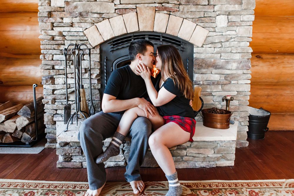 Cozy romantic scene with a couple sharing an intimate moment in front of a rustic stone fireplace.