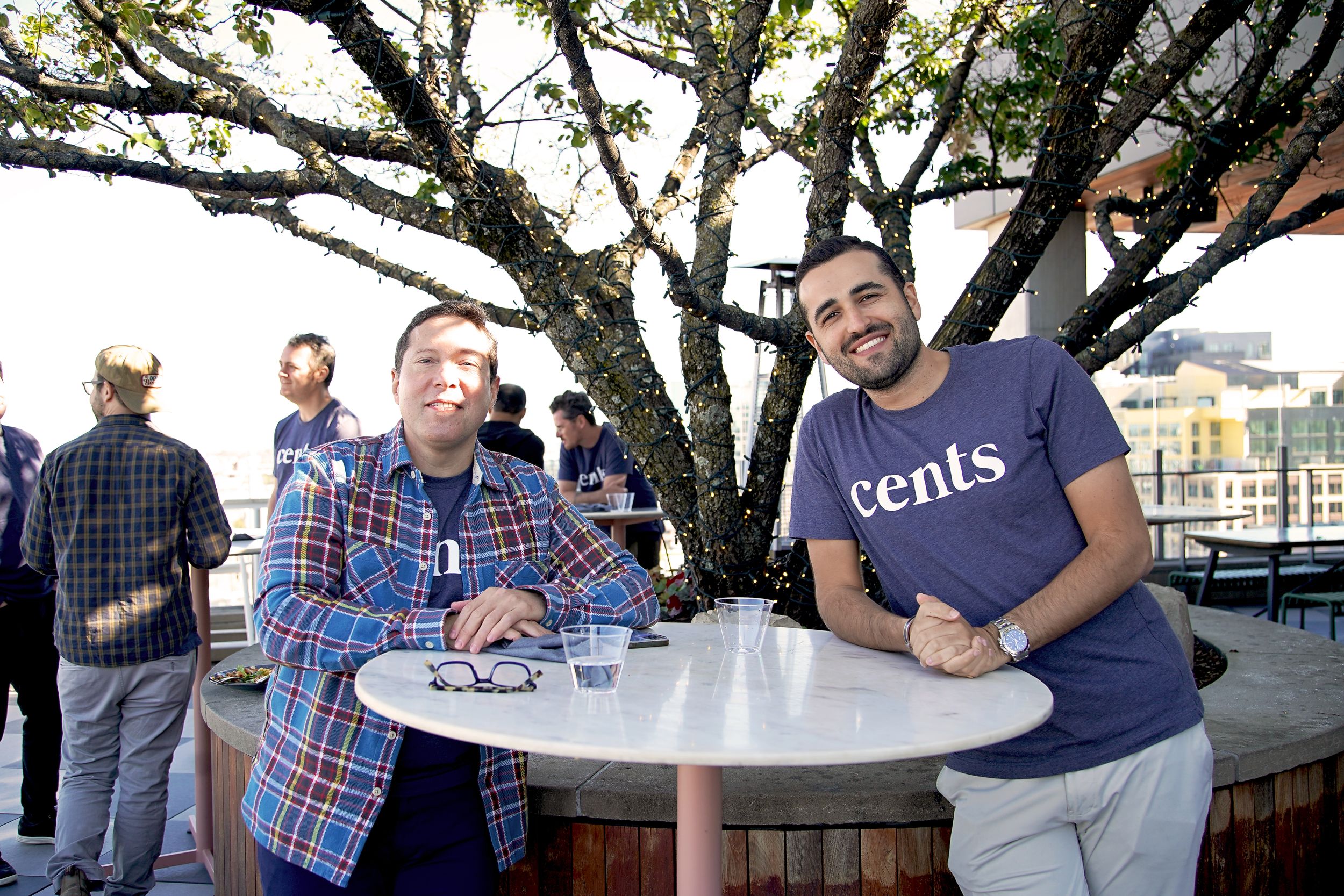 Team gathering under trees at an outdoor venue with casual seating arrangements.