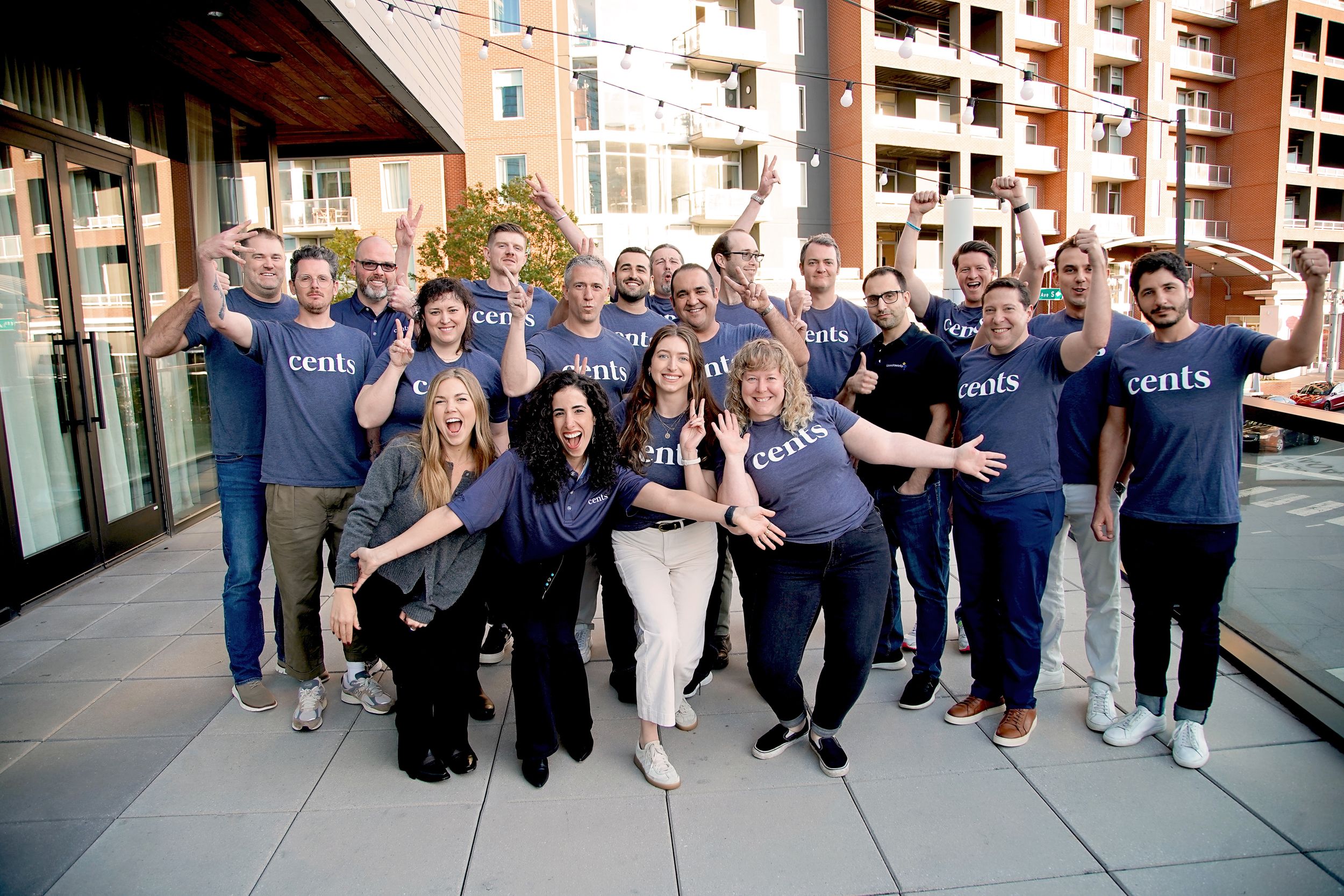Team members in matching blue shirts posing together outside an office building.