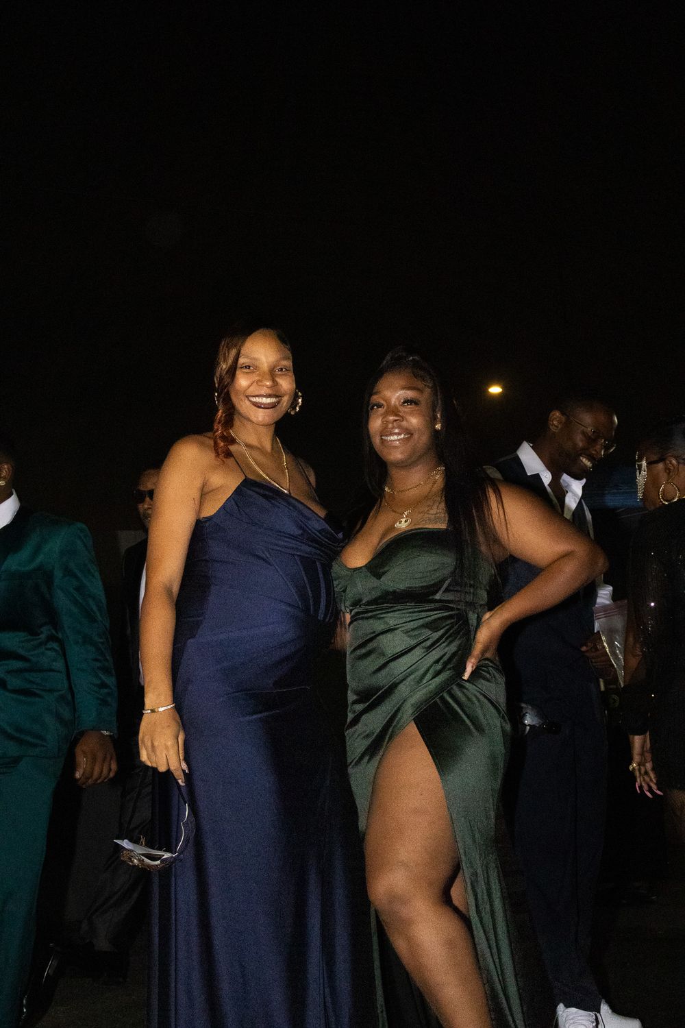 Formal event attendees pose together in elegant blue and green evening gowns.