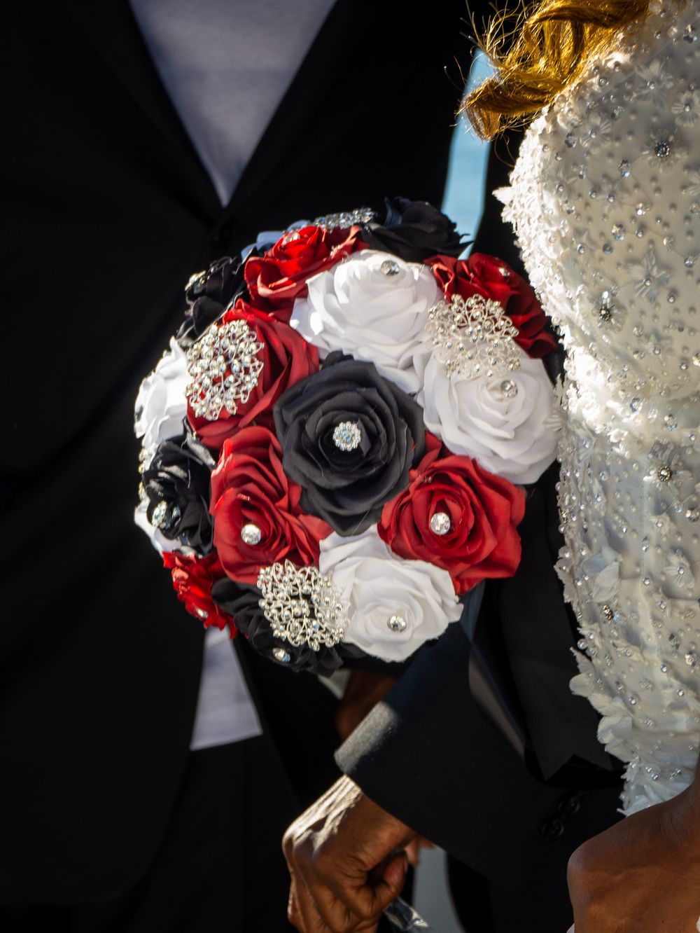 Wedding bouquets featuring elegant red, black and white roses with crystal accents against a dark background.