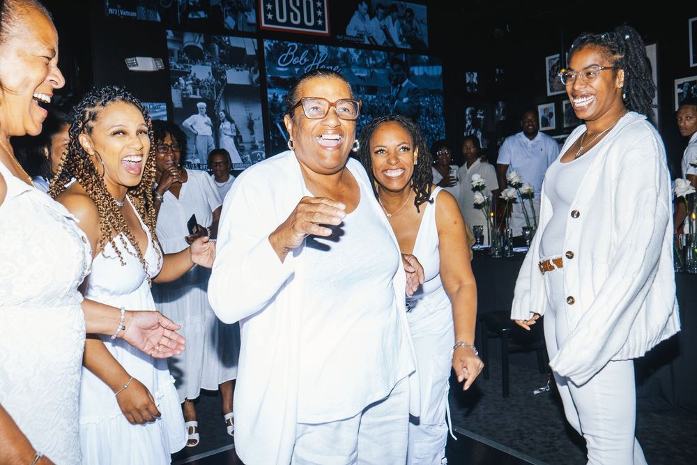 Lively party scene with guests in white clothing dancing and socializing.