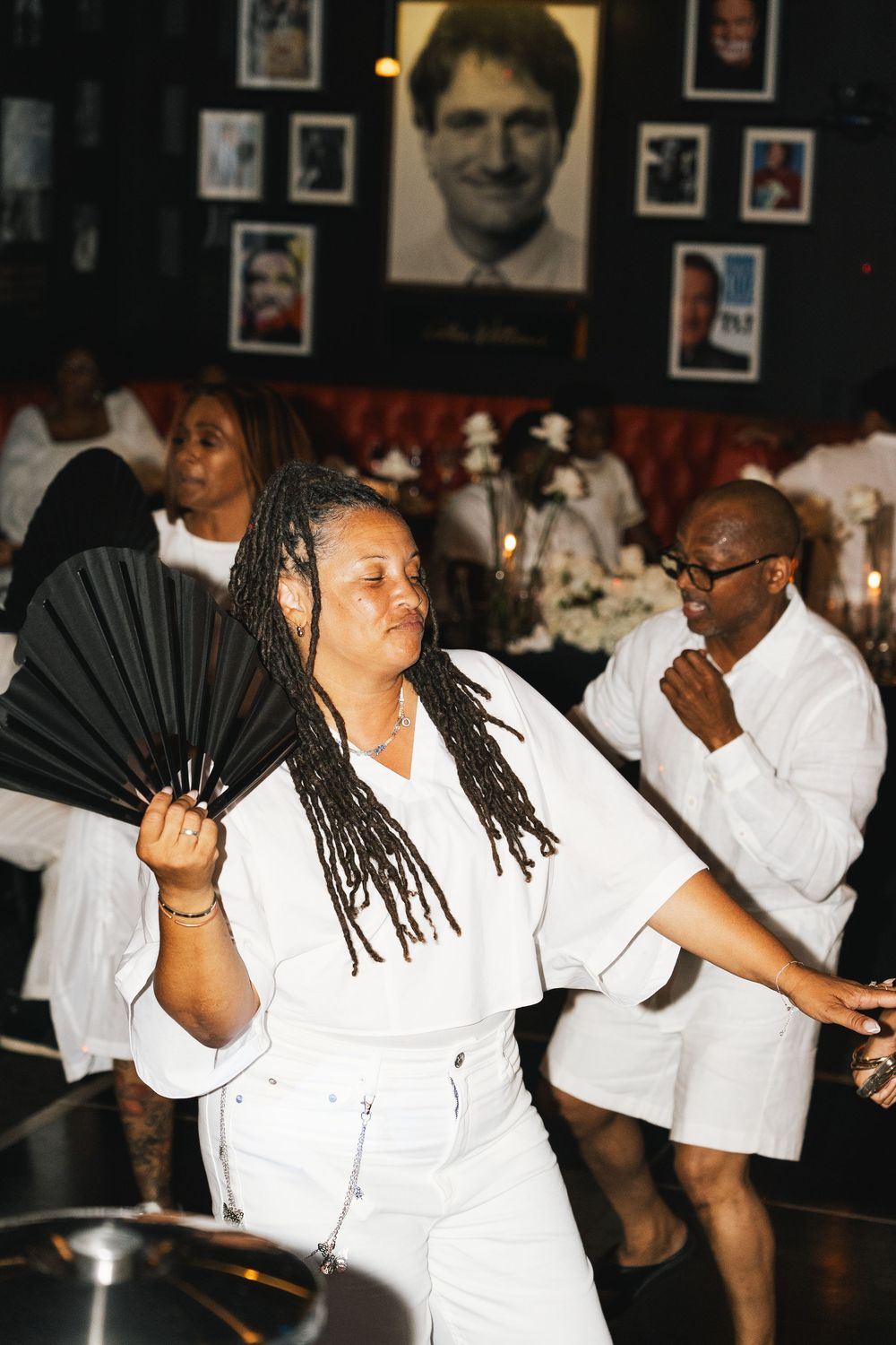 Energetic dance party scene with people in white outfits enjoying themselves on the dance floor.