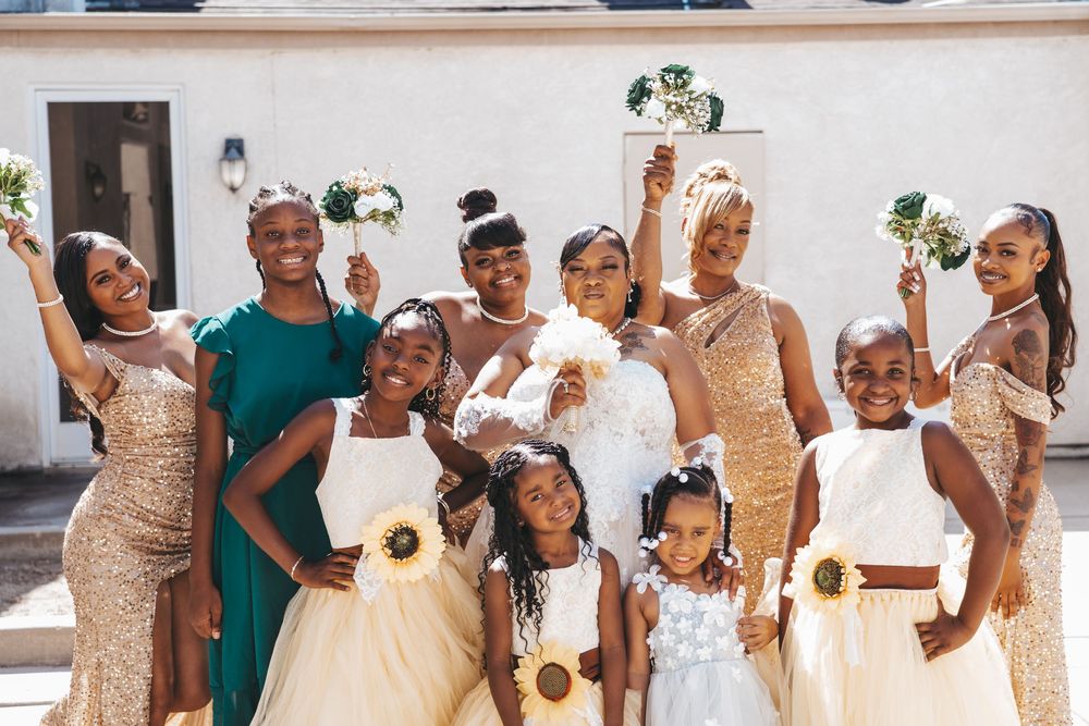 Elegant bridal party in gold sequin dresses and emerald green attire pose together outdoors.