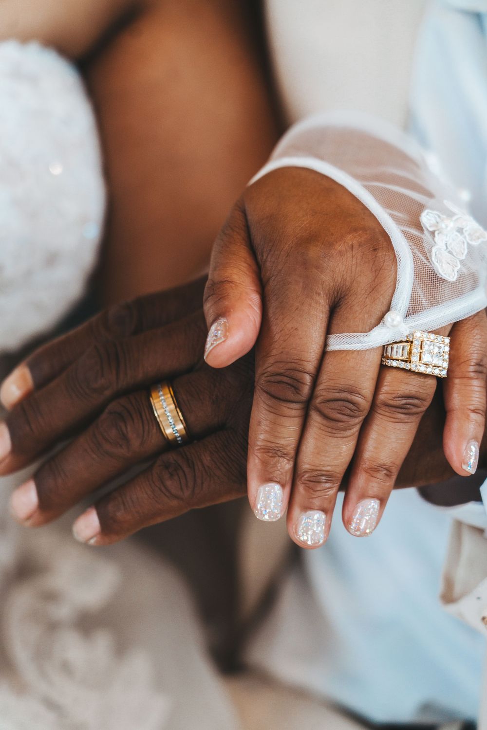 Close-up of hands showing wedding rings and white nail polish details.