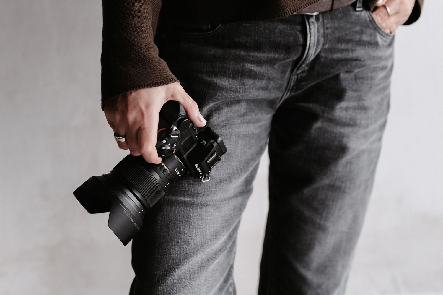 Fotografiert hält Kamera in der Hand vor dunkler Jeans- professionelle Fotografie und kreative Bildgestaltung.