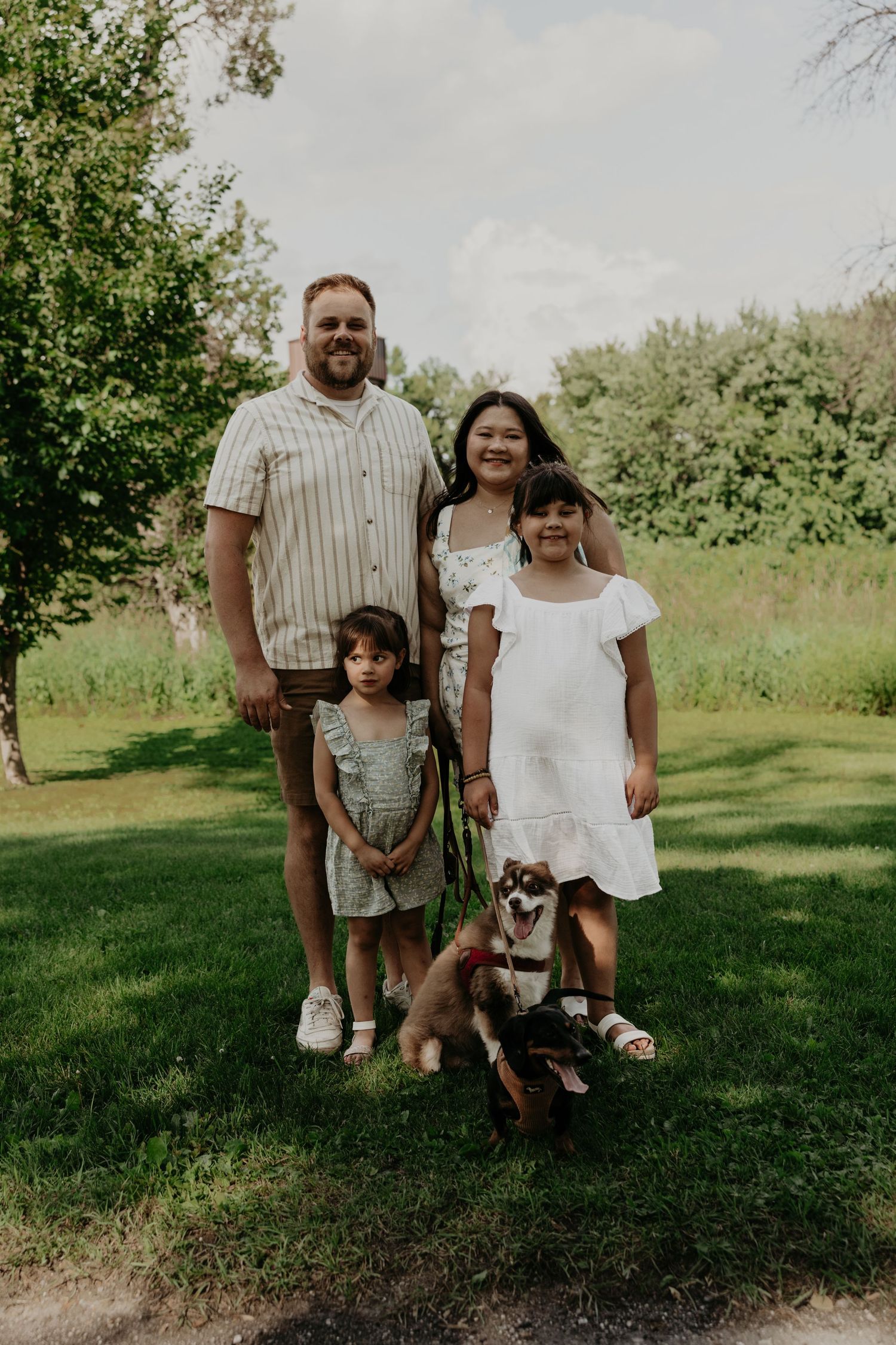 Family portrait session on grass with children in casual summer attire.