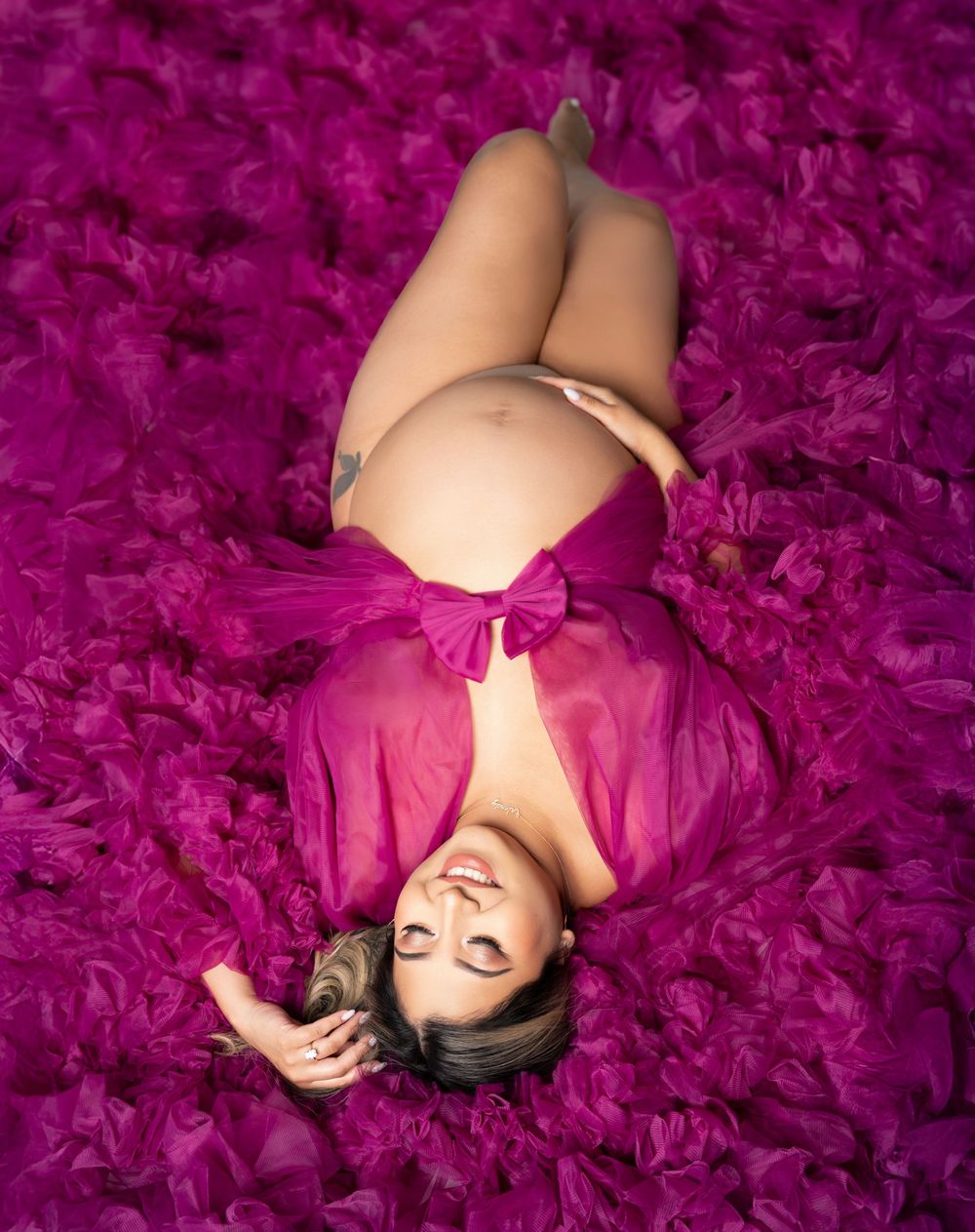 A figure in pink attire lies on a vibrant magenta textured background creating a dreamy artistic portrait.