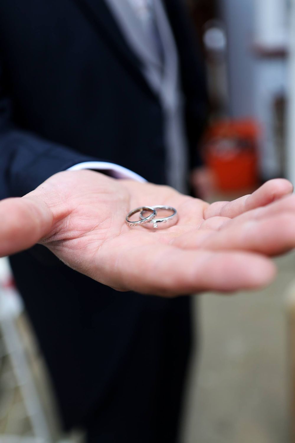 Wedding rings displayed on an outstretched palm in soft focus.