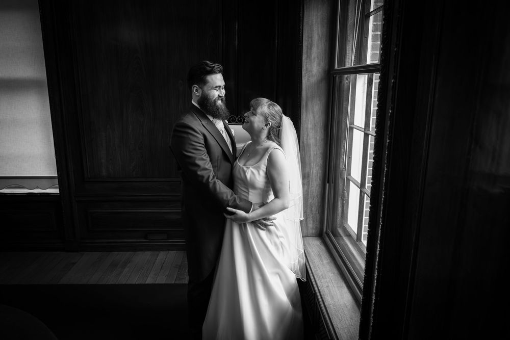 Intimate wedding moments captured by window light in dramatic black and white.