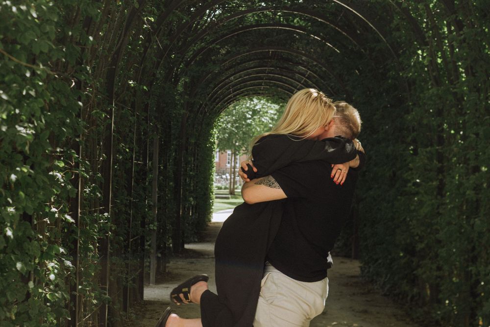 Romantic embrace under a green garden tunnel archway.