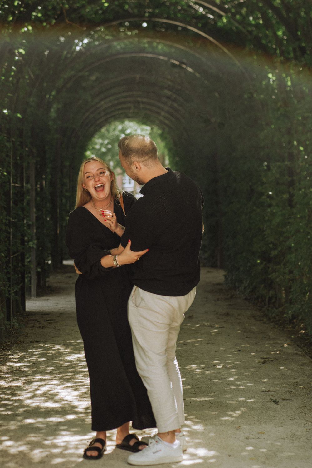 Joyful moment shared between couple in garden tunnel pathway.