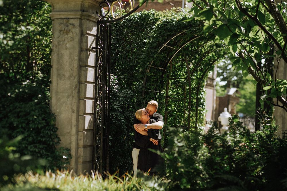 Romantic moment captured between two people in a garden with greenery and sunlight.