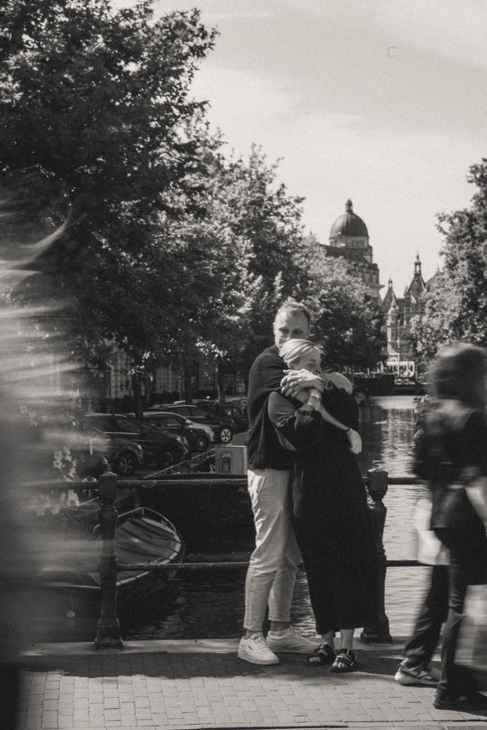 Black and white street scene showing people moving in motion blur near historic buildings.
