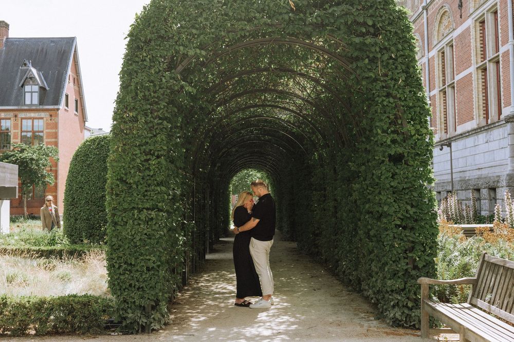 Couple embracing under a lush green garden archway tunnel.