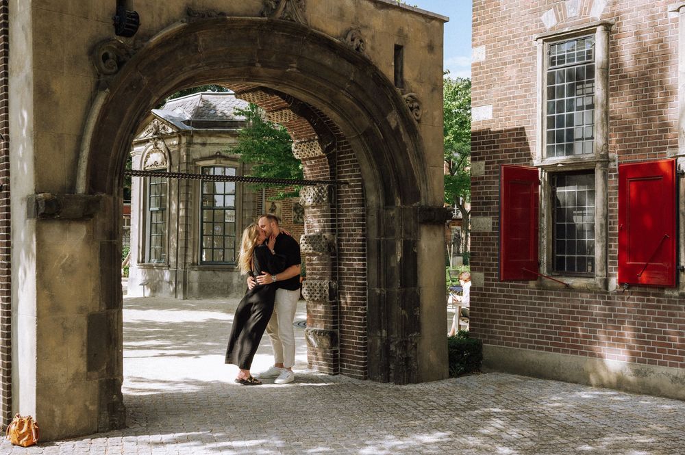 Romantic moment captured under a historic stone archway entrance.