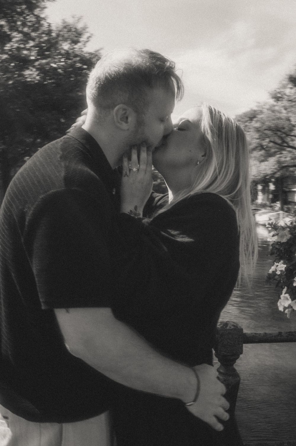 Intimate black and white portrait of a couple sharing a passionate kiss outdoors.