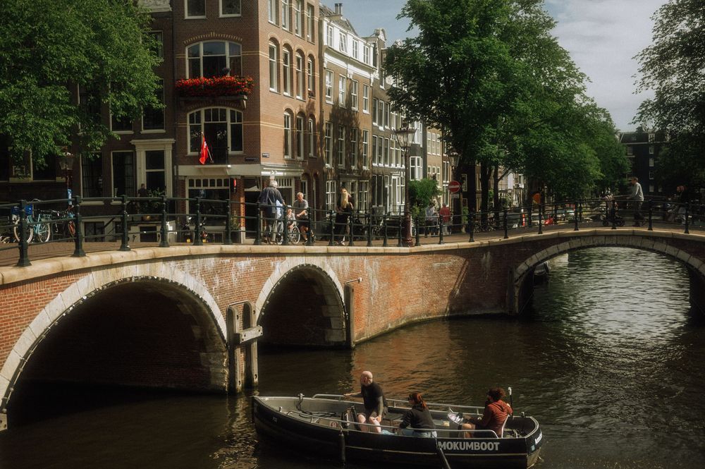 Amsterdam canal scene with historic buildings and bridges under cloudy skies.