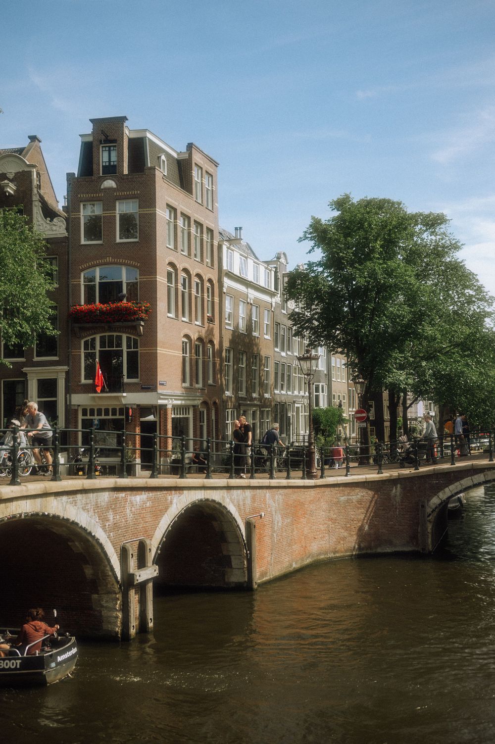 Classic Amsterdam canal scene with historic buildings and bridge over waterway.