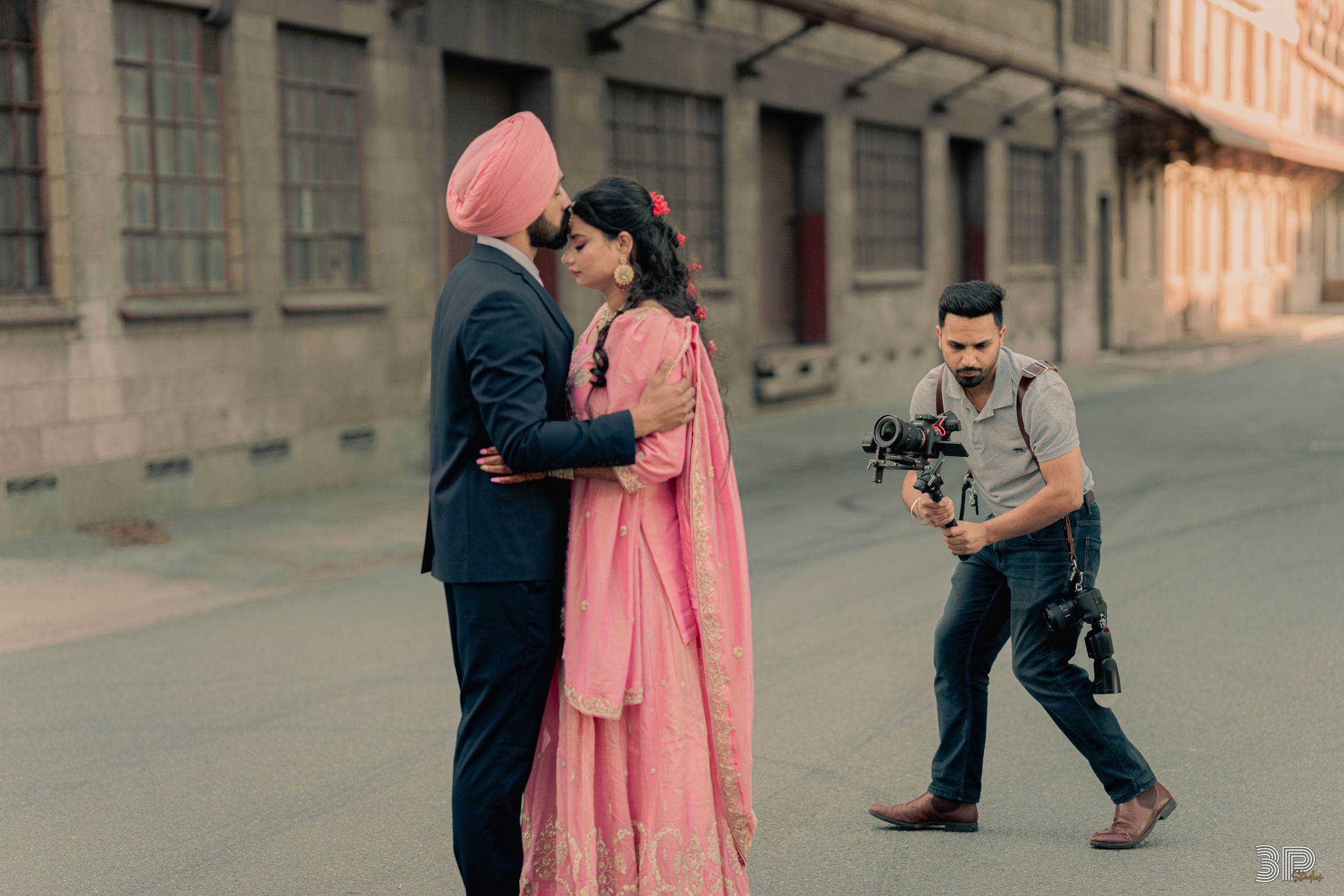 Videographer capturing a romantic moment between the bride and groom during their wedding day, with a professional camera setup.