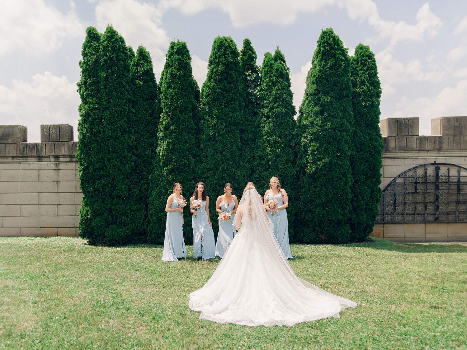 A romantic wedding portrait against a wall of tall green cypress trees.
