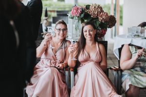 Bridesmaids in pink dresses share a celebratory toast at a wedding reception.