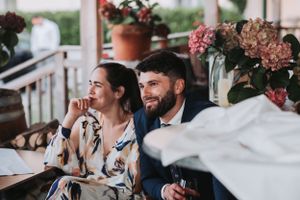 Wedding guests relaxing on a porch decorated with pink flowers.
