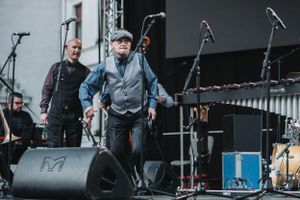 Musicians perform on stage with various instruments and microphone setups.
