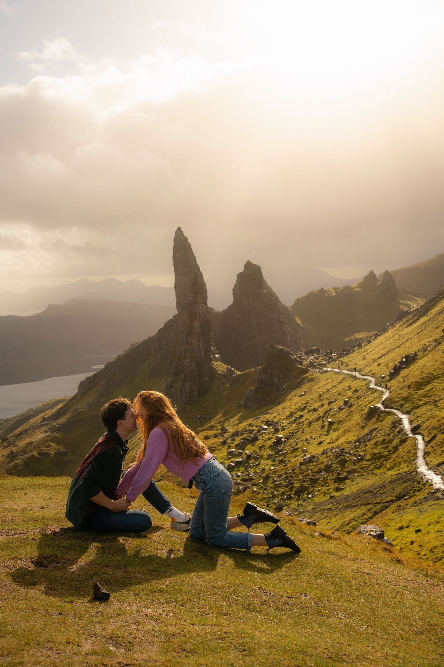 A couple in front of the iconic Old Man of Storr, the rugged landscape framing their love. Captured by Kaci Madden Photography, 2024.