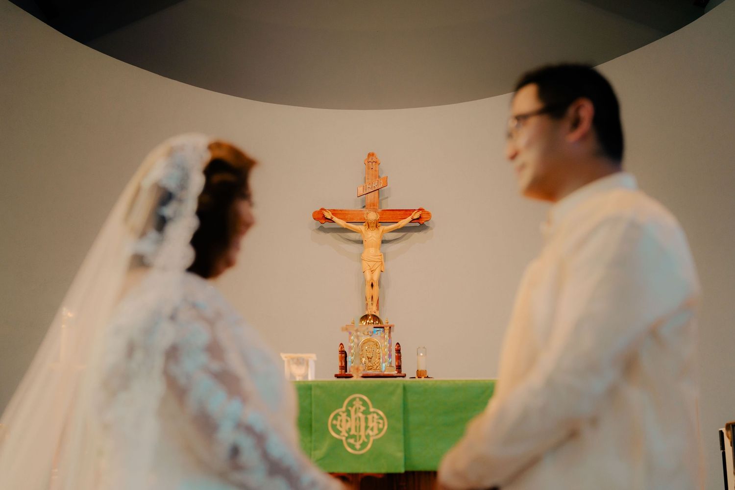 Catholic wedding ceremony scene with crucifix altar and traditional white dress.