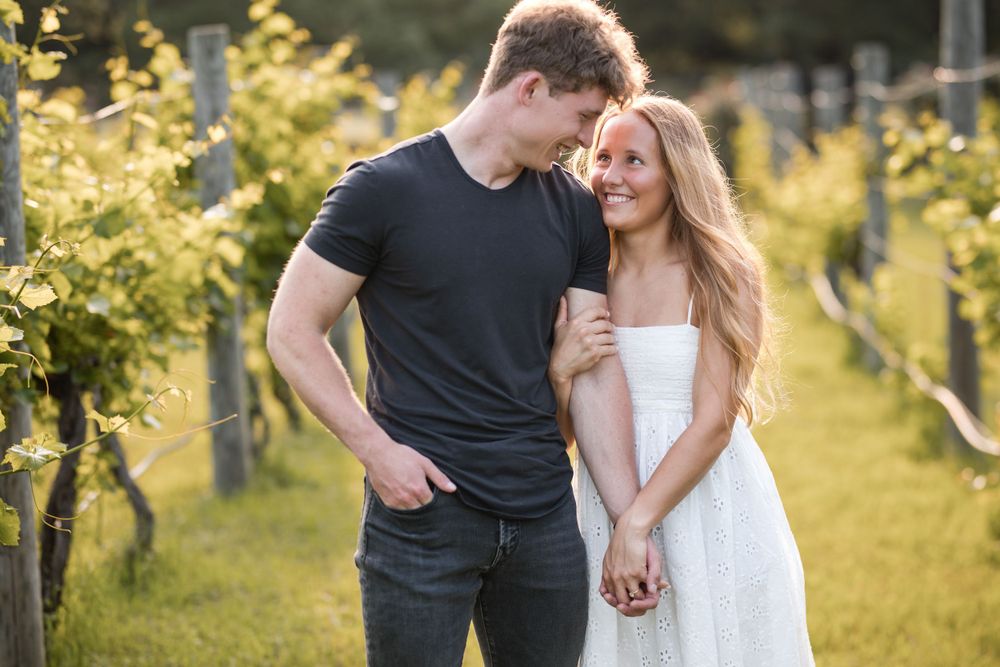 A couple shares an intimate moment while walking through a sunlit vineyard on a warm afternoon.