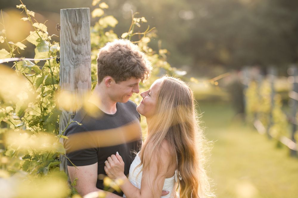 A loving couple share a tender moment together in a sunlit garden with golden bokeh and nature elements.