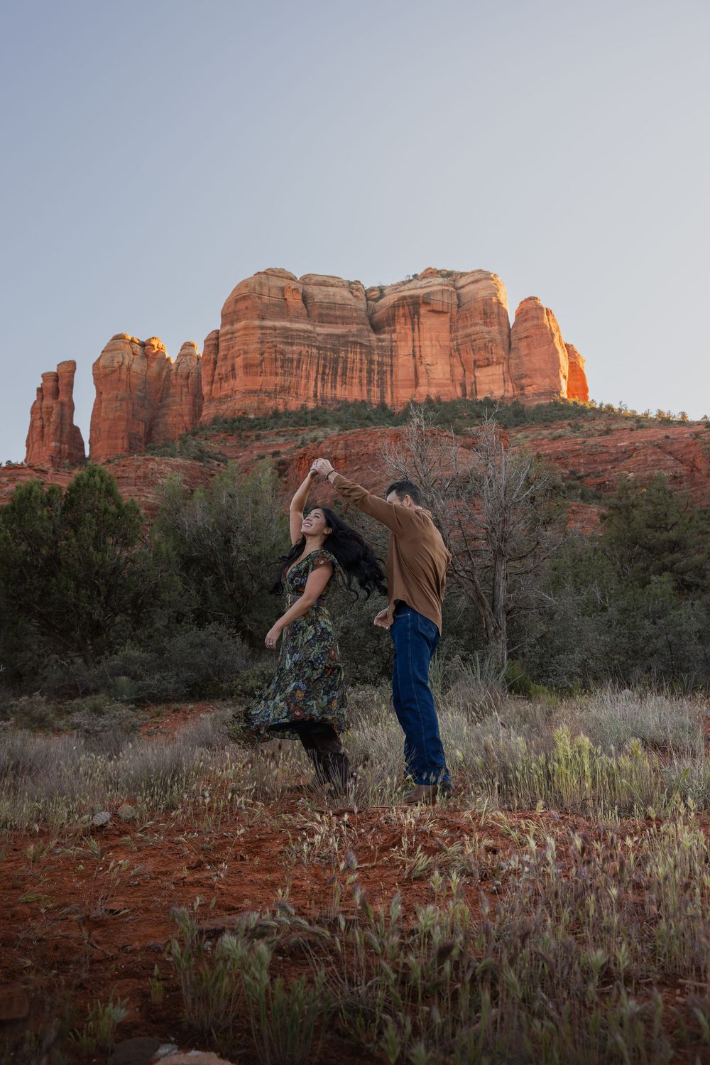 Couple dancing romantically in front of Cathedral Rock formations in Sedona at golden hour.