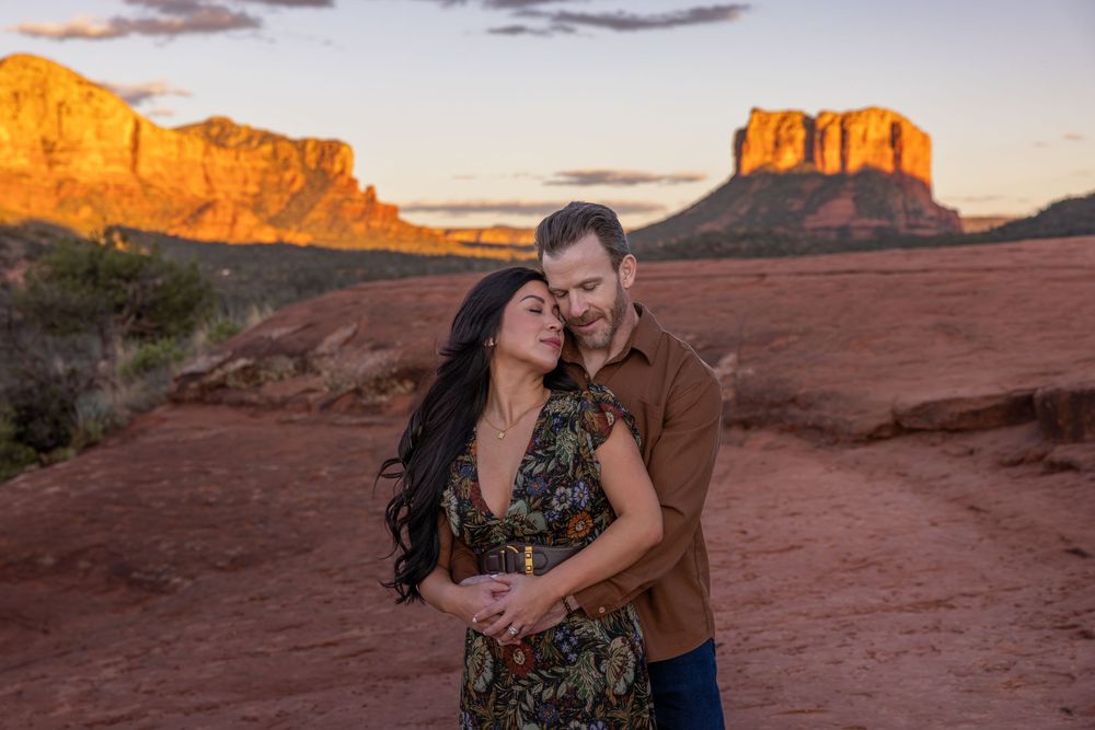 Romantic couple sharing a tender moment with stunning Sedona red rock formations at golden hour.