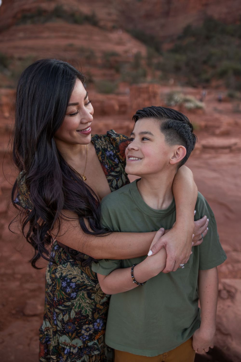 Mother and son sharing a warm embrace while smiling at each other against Sedona red rocks.