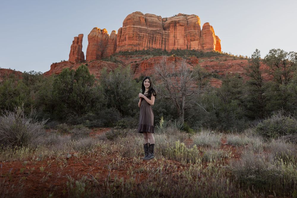 Woman standing peacefully in a meadow with stunning Cathedral Rock in Sedona at dusk.