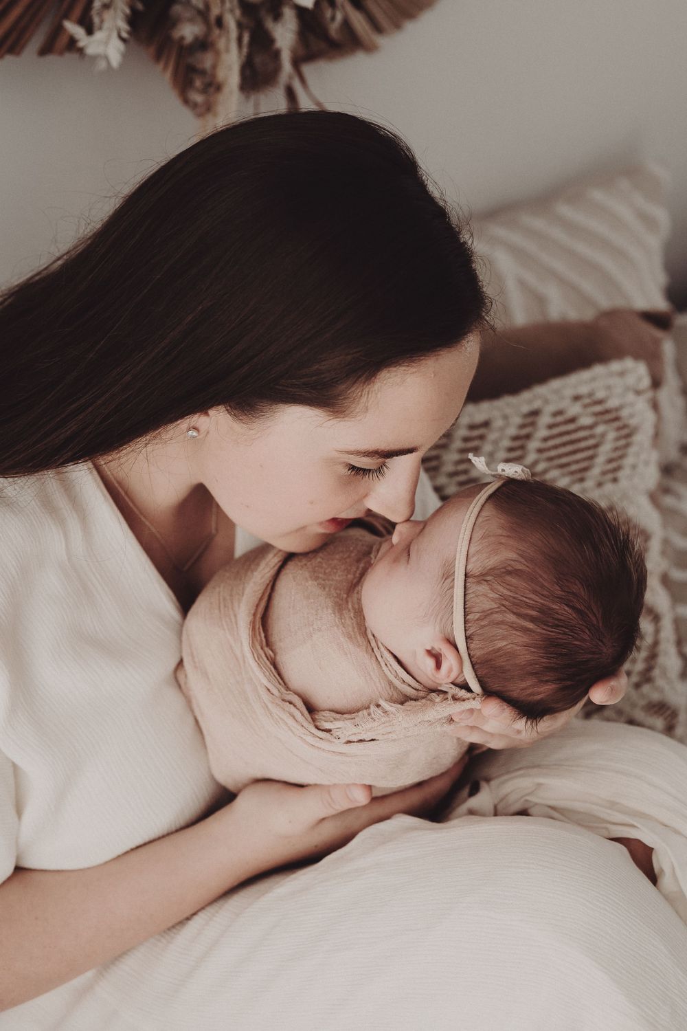 A tender moment captured showing a parent in white cradling and bonding with their newborn baby.