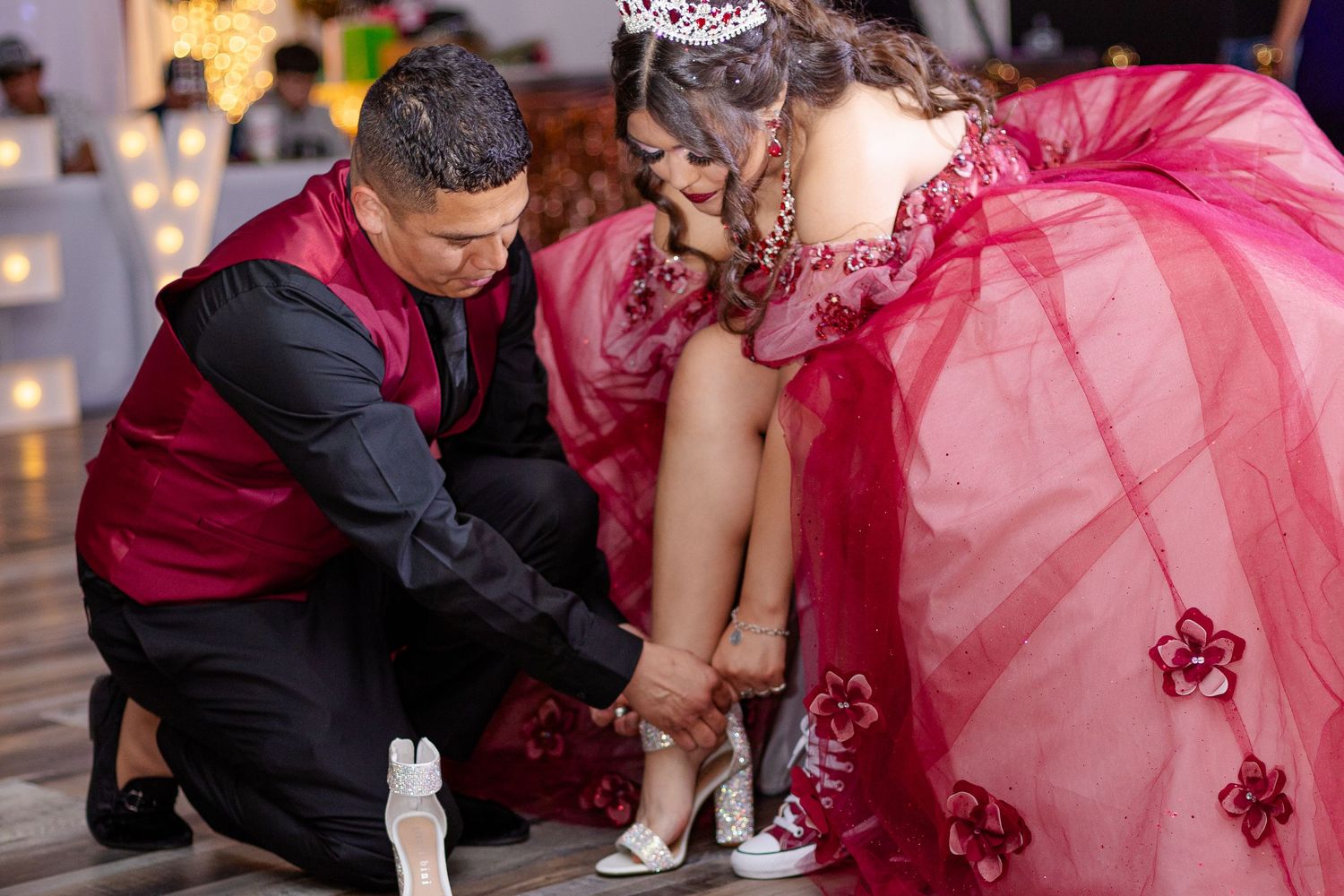 Traditional quinceañera shoe ceremony moment in a formal ballroom setting.