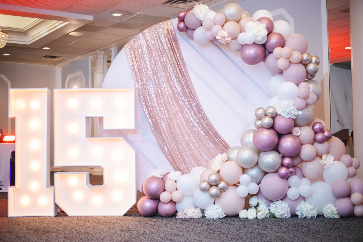 Elegant balloon arch installation with pink and white balloons against light colored wall.