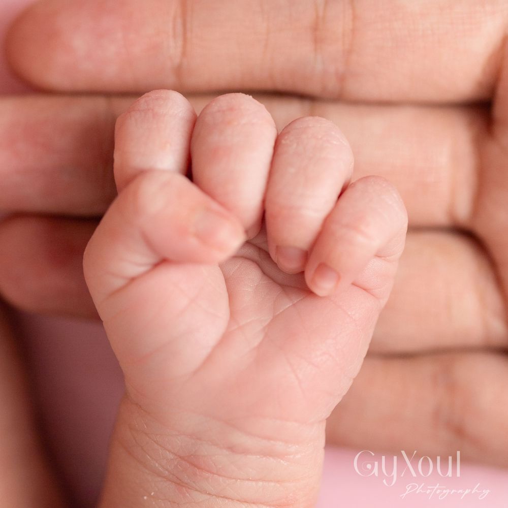 Close-up of tiny newborn baby's hand curled into a fist.