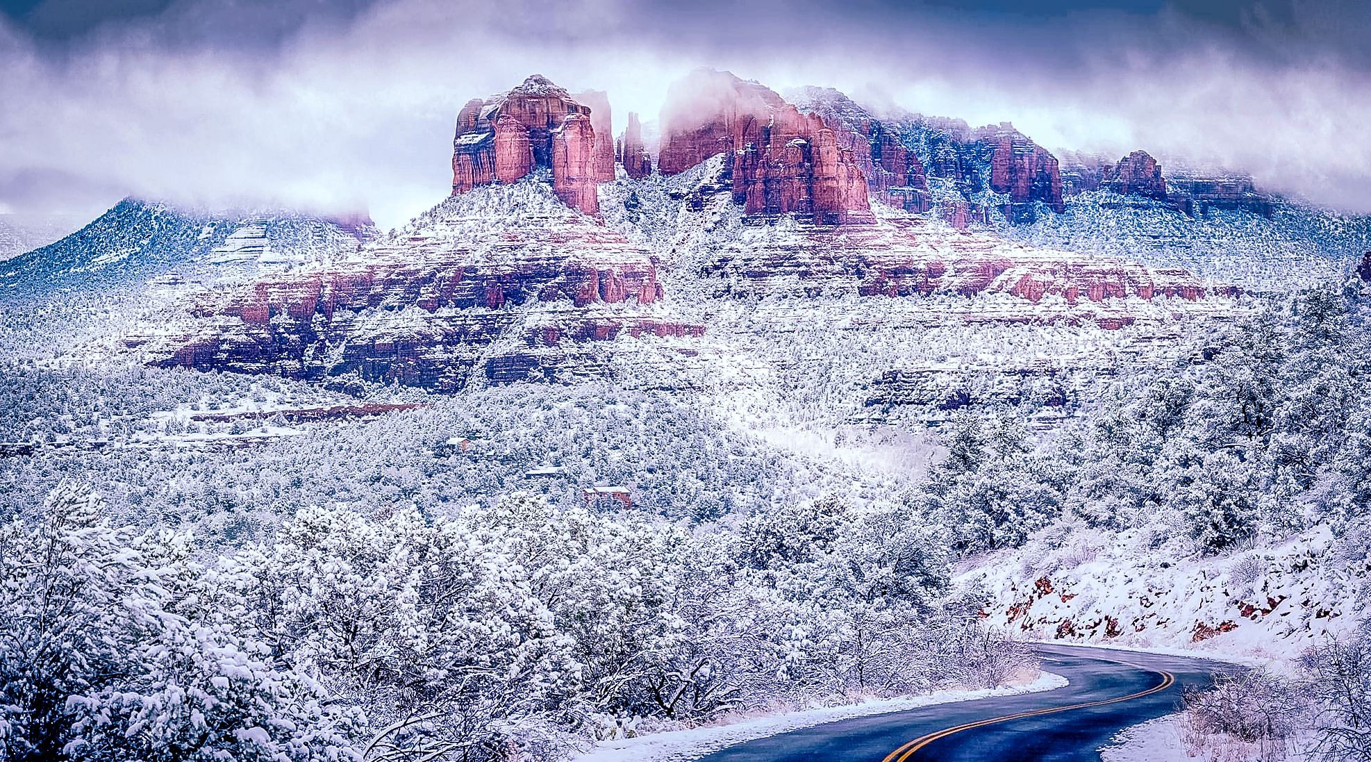 Snow-covered red rock formations in Sedona against cloudy winter sky.