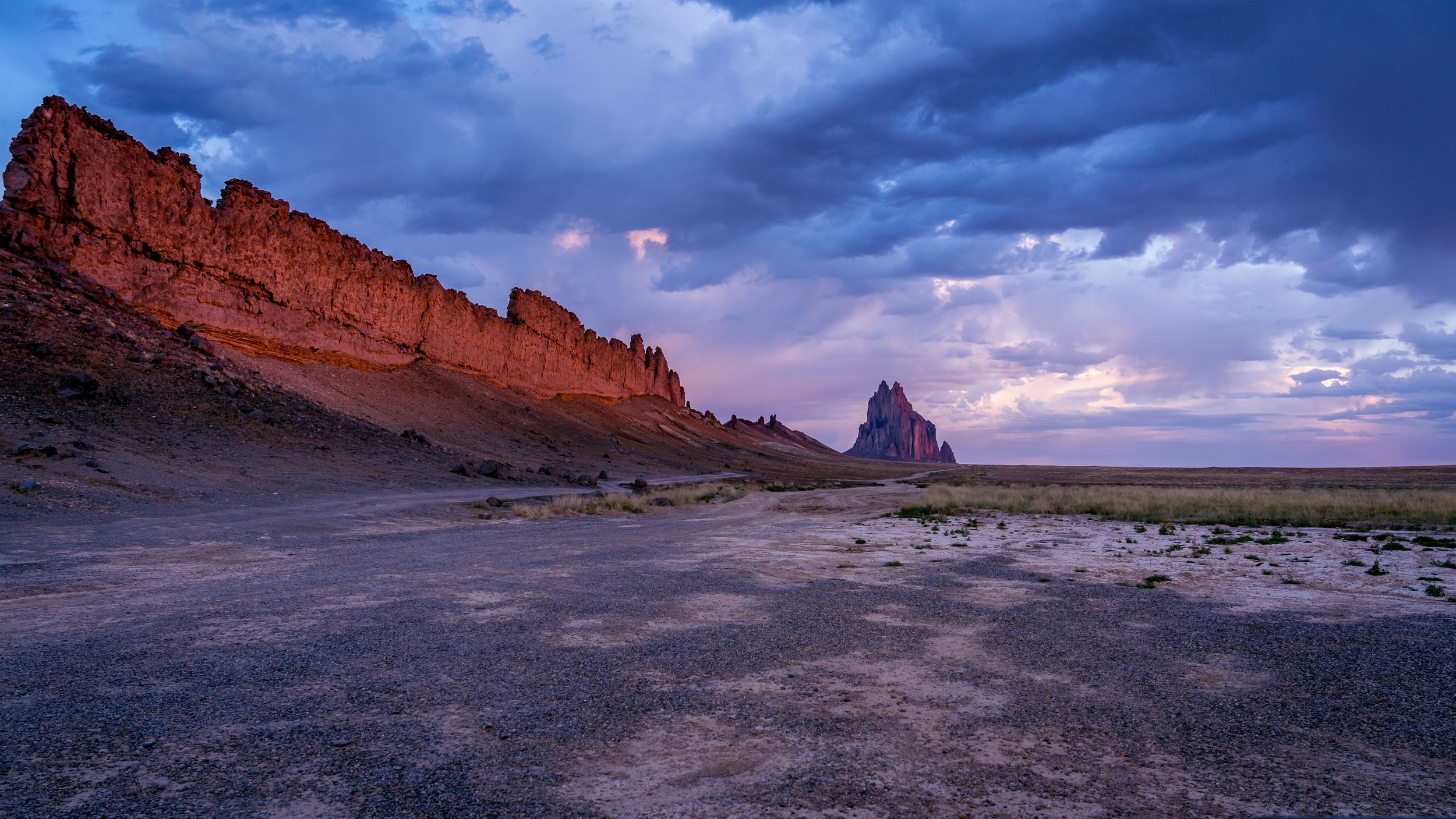 Dramatic red rock formations at sunset with stormy clouds in the desert landscape.