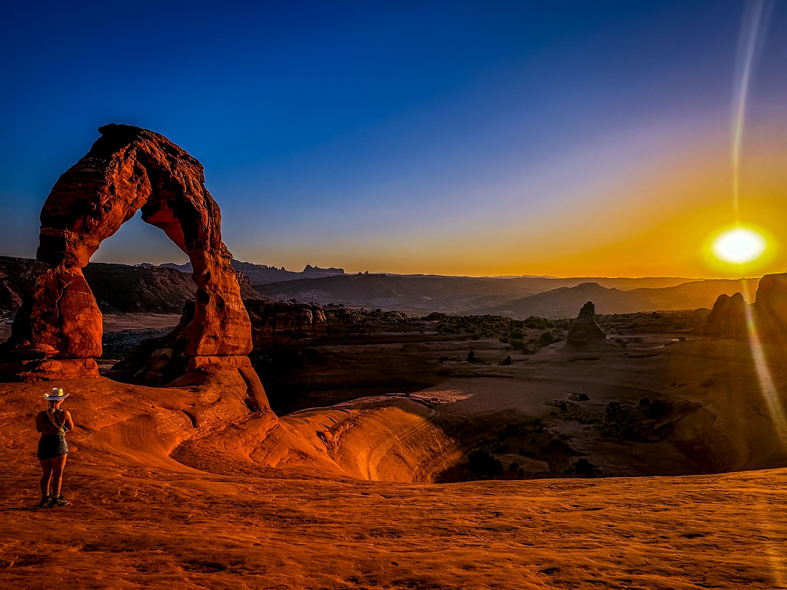 Delicate Arch silhouetted against golden sunset sky in Arches National Park.