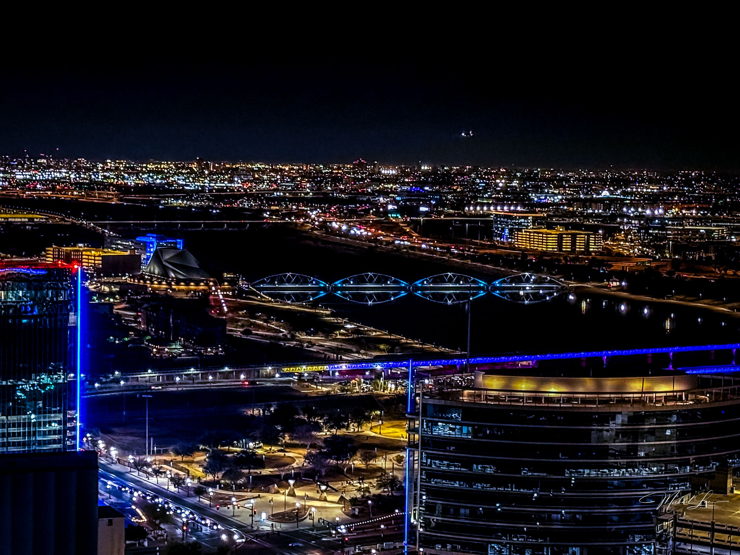 Illuminated cityscape at night with modern buildings and blue light features.