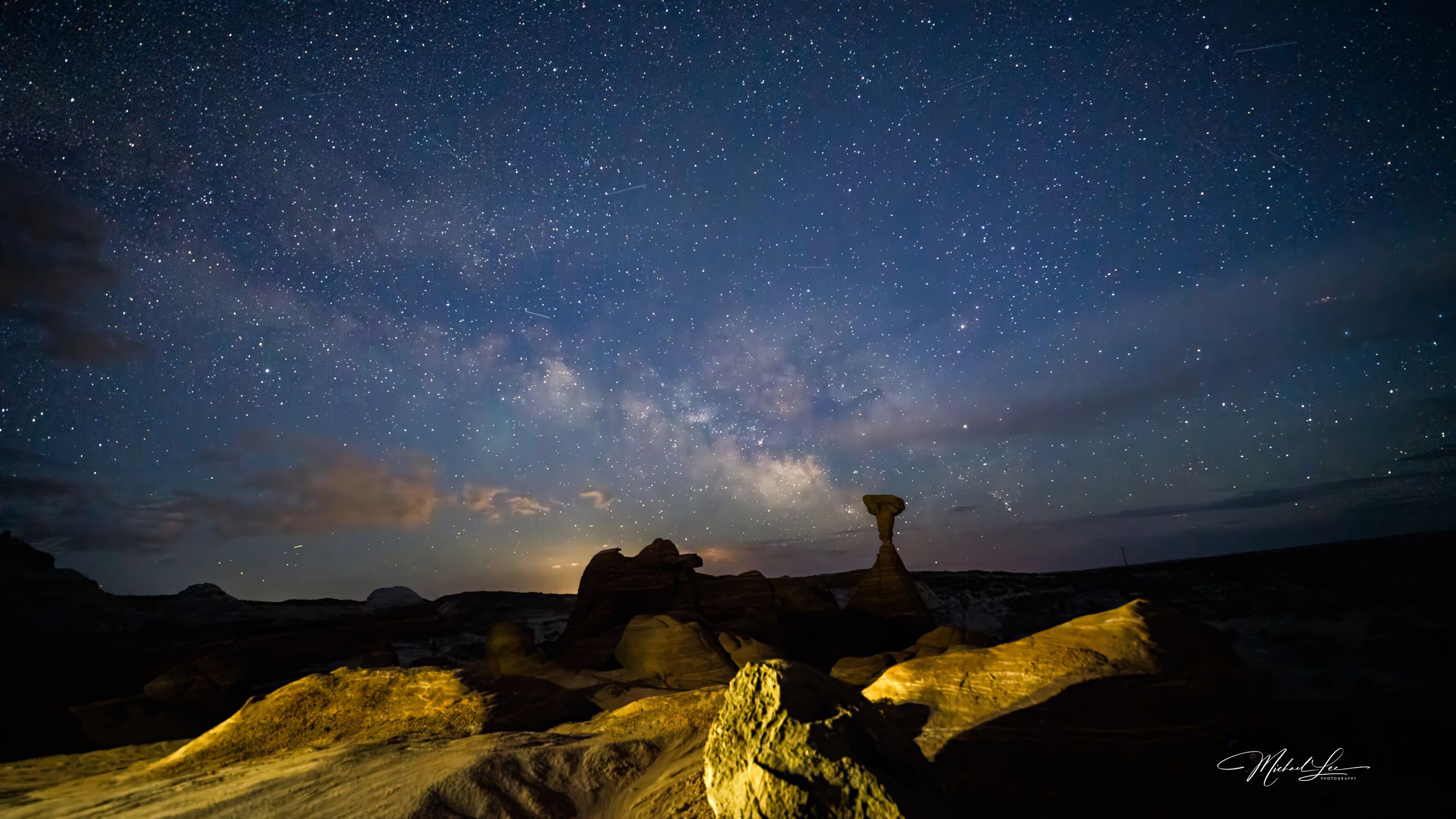 Stunning Milky Way galaxy visible over rock formations in a desert landscape at night.
