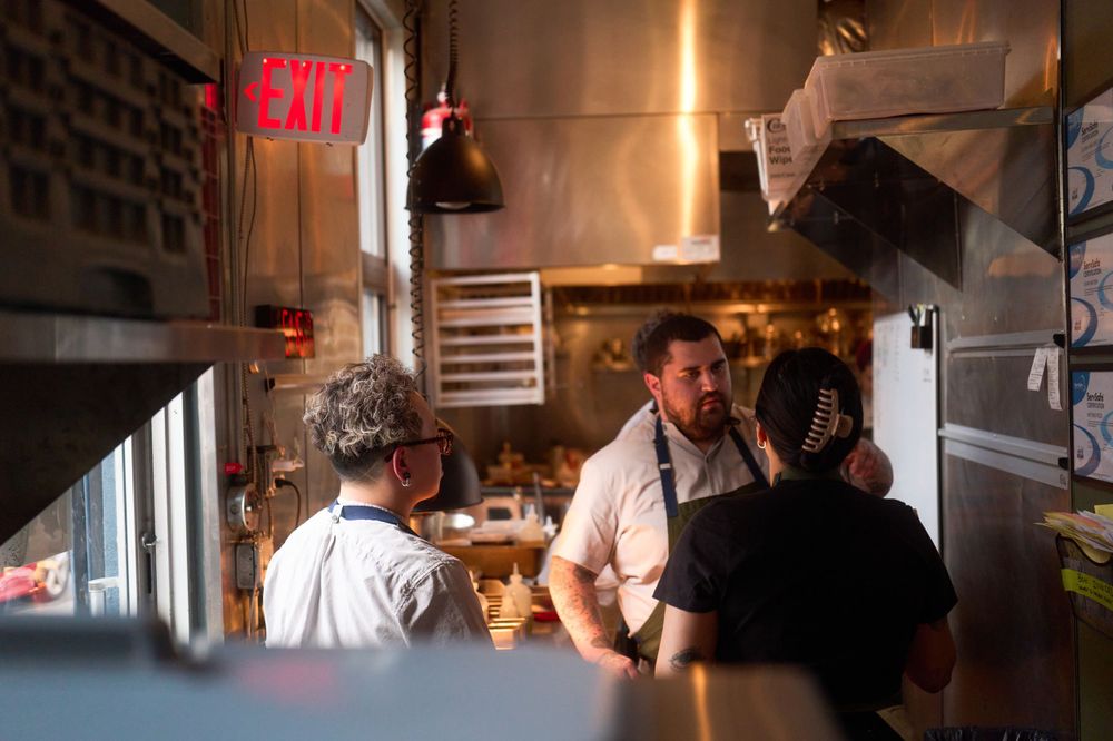 Busy restaurant kitchen staff working together during service under warm lighting.